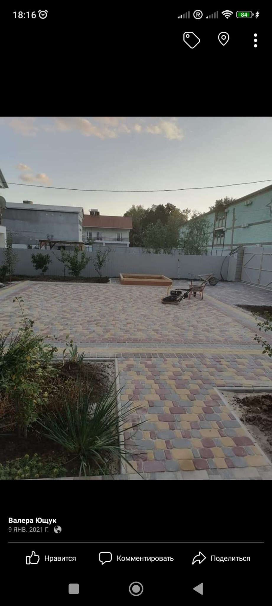 Ułożona kolorowa kostka brukowa na posesji, widoczna ubijarka wibracyjna i piaskownica w tle.