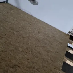 Płyta OSB ułożona na legarach drewnianych, widoczne otwory w suficie z wystającymi rurami i przewodami.