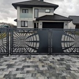 Łukasz Binkowski - Nowoczesna brama wjazdowa z geometrycznym wzorem tunelu na tle domu z garażem i kostki brukowej.