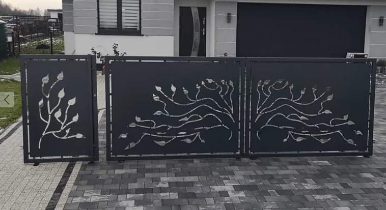 Nowoczesna, czarna brama wjazdowa z laserowo wycinanym motywem drzewa i liści, zamontowana w Sycowie, na tle domu z szarą elewacją i kostką brukową.