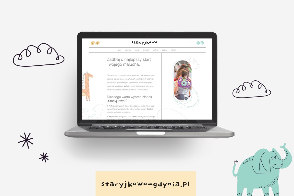 Laptop wyświetla stronę internetową żłobka Stacyjkowo Gdynia Wielki Kack z ilustracjami chmurek, słonia i żyrafy. Na ekranie widoczna dziewczynka robiąca zdjęcie zabawką. Domena żłobka wypisana...