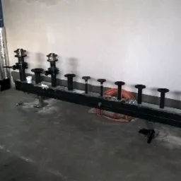 Rozdzielacz instalacji grzewczej z zaworami i rurami w surowym pomieszczeniu, widoczne ślady po pracach wykończeniowych na ścianach i podłodze.