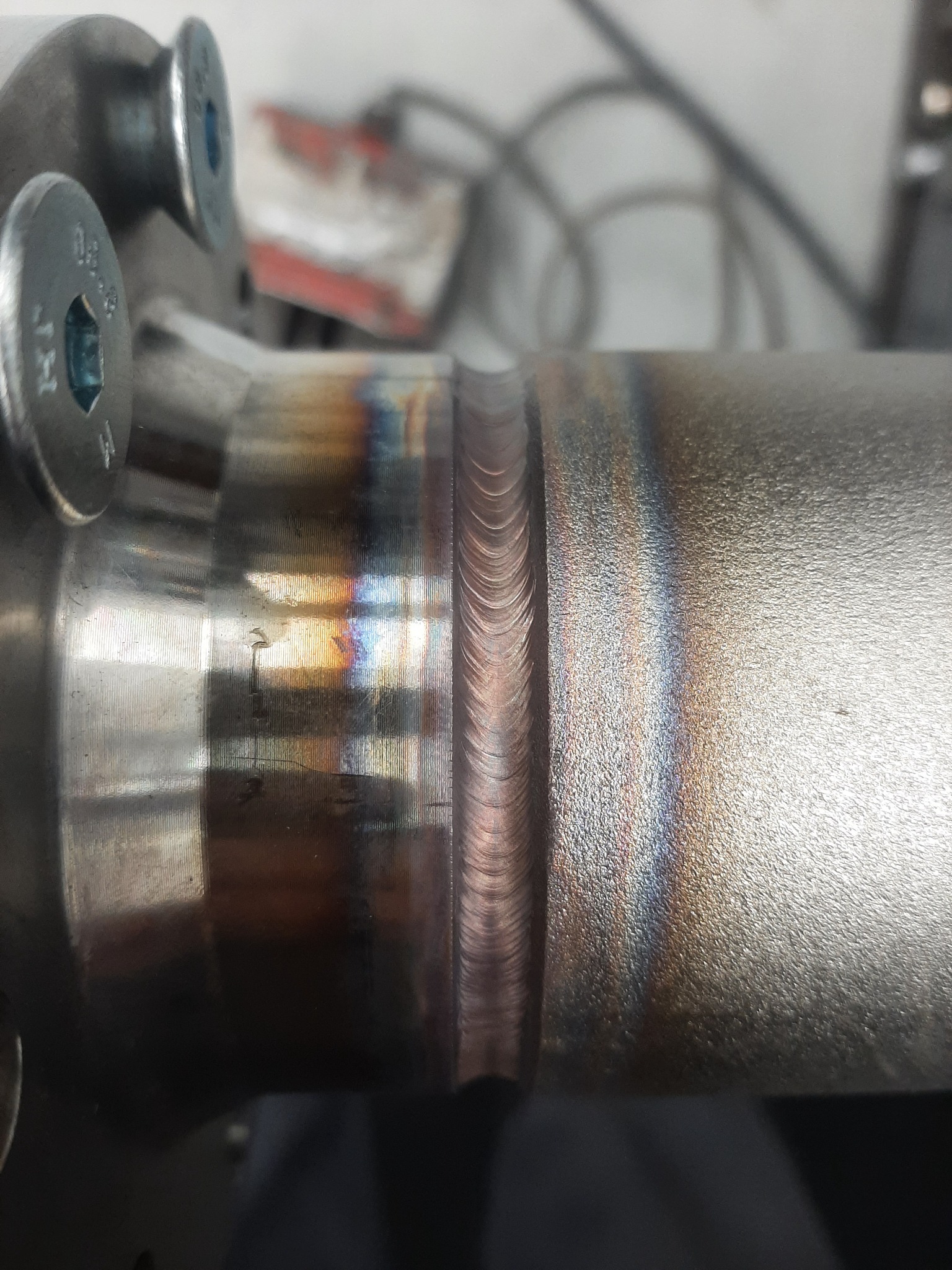 Szczegółowe ujęcie spoiny na metalowej rurze w Słupsku, widoczne ślady obróbki i charakterystyczne zabarwienie termiczne.