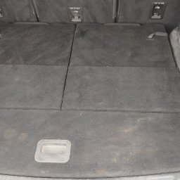 CarService- Dominik Muszkieta - Pusta, czarna przestrzeń bagażowa samochodu typu van z trzema składanymi panelami podłogowymi i uchwytami mocującymi na ścianach bocznych.