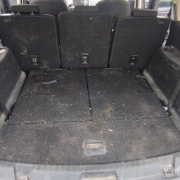 CarService- Dominik Muszkieta - Wnętrze bagażnika SUV-a w widoku od tyłu, z widocznymi złożonymi siedzeniami i zabrudzeniami na wykładzinie.