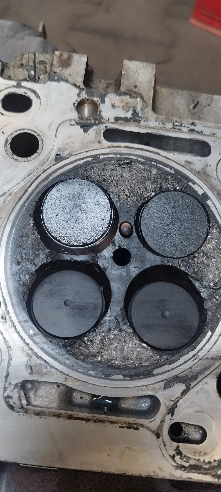 Głowica silnika spalinowego z widocznymi nagarami, przedstawiająca zużycie i potrzebę czyszczenia lub regeneracji zaworów.