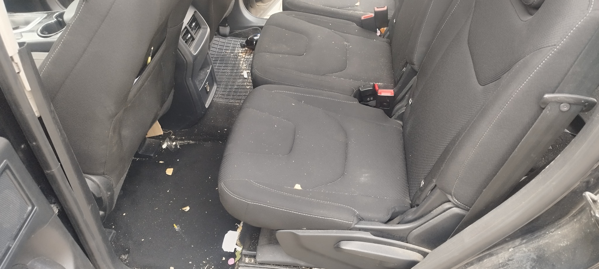 Wnętrze samochodu z widocznymi zabrudzeniami na siedzeniach i podłodze, wymagające czyszczenia.
