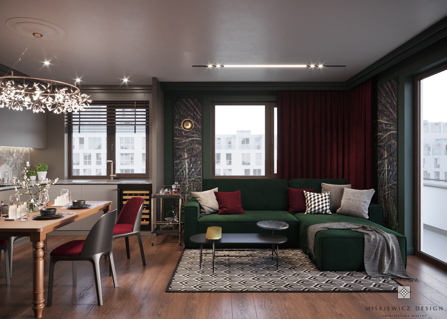 Wnętrze salonu z aneksem kuchennym, z ciemnozieloną sofą narożną, geometrycznym dywanem i drewnianym stołem jadalnym z krzesłami w kolorze bordo, oświetlone dekoracyjnym żyrandolem i lampą sufitową.