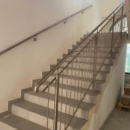 TECH-WELD Wojciech Putrym - Wnętrze klatki schodowej w Lubsku z metalowymi schodami i prostą, nierdzewną balustradą oraz poręczą, w trakcie wykańczania.