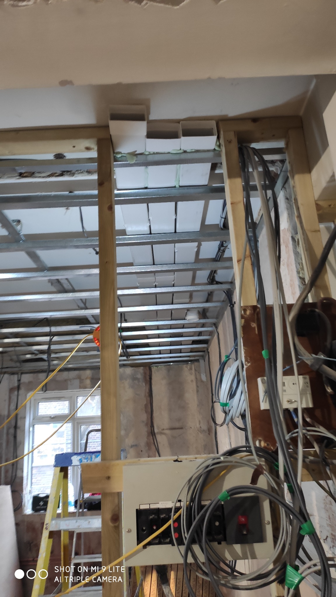 Montaż metalowej konstrukcji sufitu podwieszanego z widocznymi elementami instalacji w trakcie remontu w London.