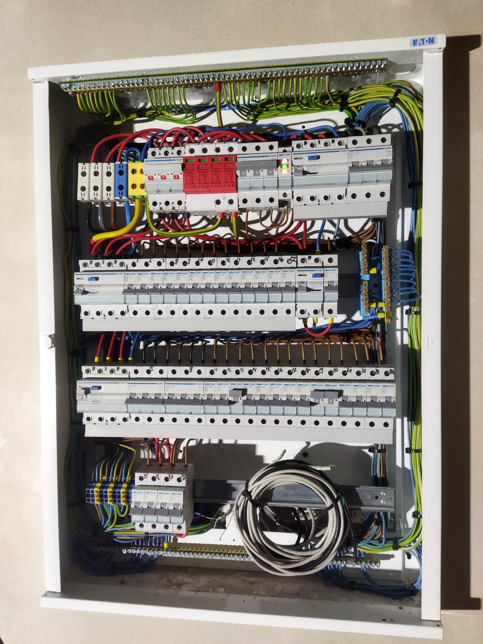 Rozdzielnica elektryczna Eaton z zainstalowanymi bezpiecznikami Hager, okablowaniem i listwami zaciskowymi. Widoczne przewody w różnych kolorach.