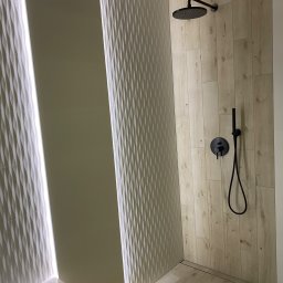 HD wykończenia wnetrz - Nowoczesna kabina prysznicowa z drewnopodobnymi płytkami, czarną armaturą i dekoracyjnymi panelami 3D z podświetleniem LED.
