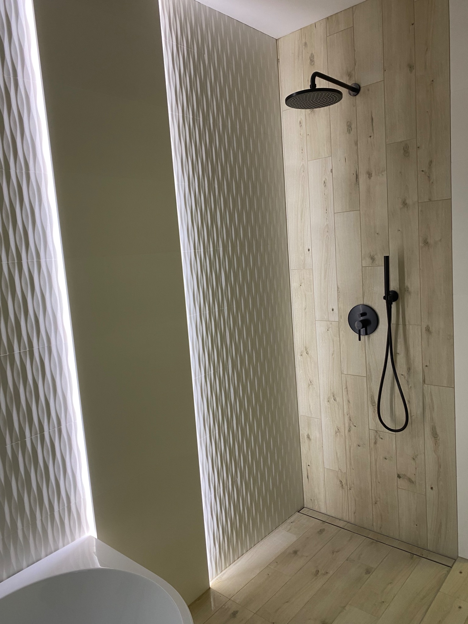 Nowoczesna kabina prysznicowa z drewnopodobnymi płytkami, czarną armaturą i dekoracyjnymi panelami 3D z podświetleniem LED.