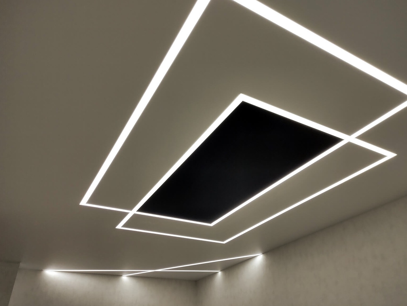 Nowoczesne oświetlenie sufitowe z prostokątnymi panelami LED, tworzącymi geometryczny wzór na jasnoszarym suficie.