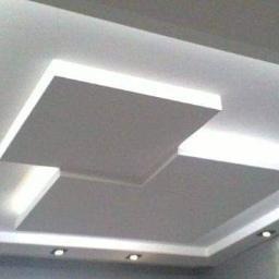 Nowoczesny sufit podwieszany z płyt kartonowo-gipsowych, oświetlenie punktowe LED, minimalistyczny design.