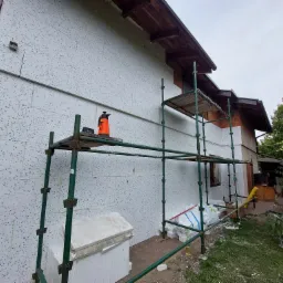 Dom w Kostrzynie w trakcie ocieplania elewacji styropianem, widoczne rusztowanie, drabina oparta o ścianę, oraz narzędzia pracy.