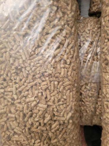 Worki wypełnione jasnobrązowym pelletem drzewnym, widoczne przez przezroczysty plastik. Delikatne refleksy światła na folii.