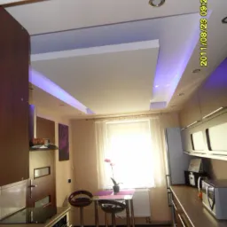 Kuchnia z podwieszanym sufitem z oświetleniem LED, widoczne zabudowy KG i nowoczesne meble kuchenne.