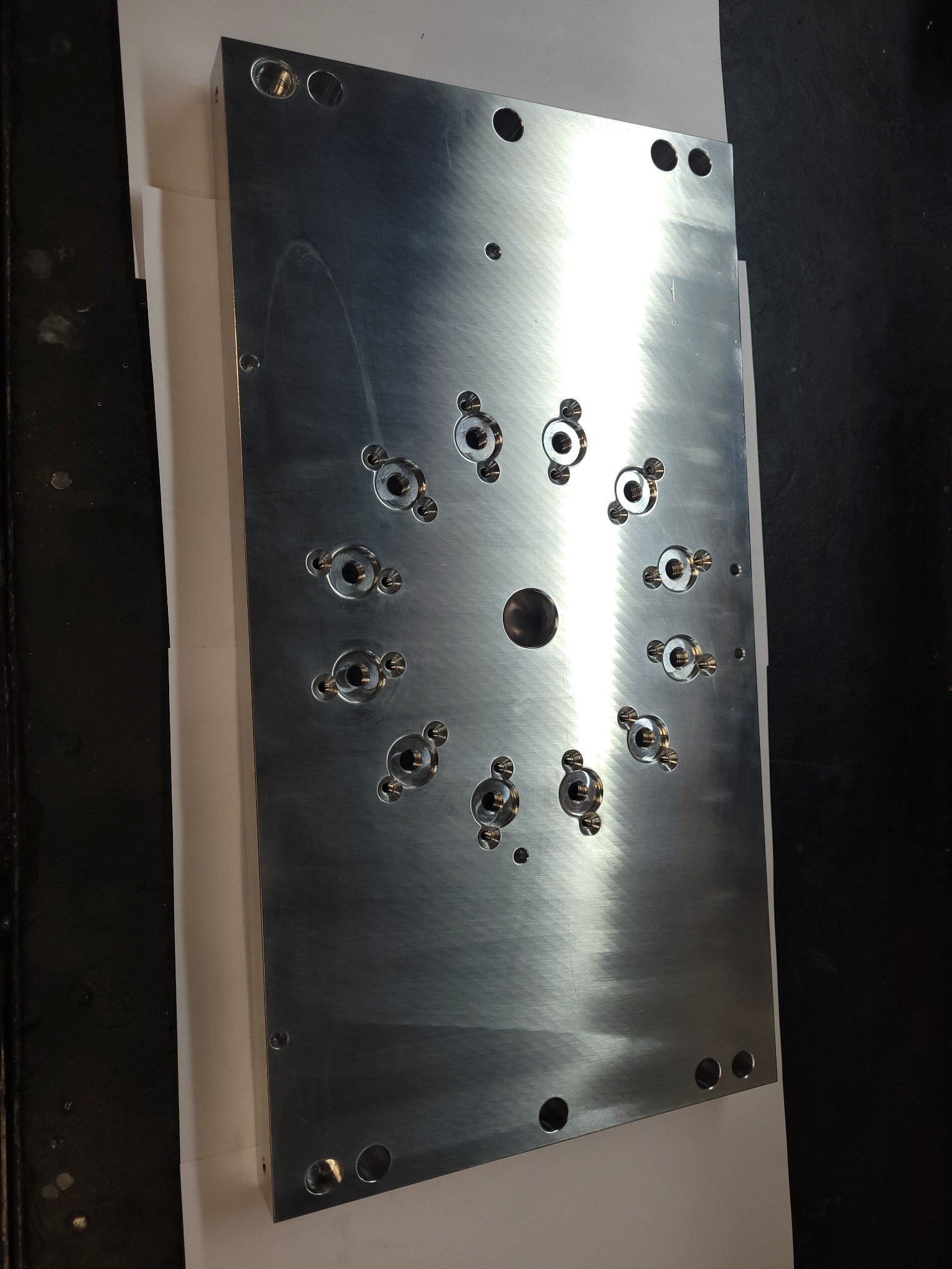 Szlifowana, aluminiowa płyta z wywierconymi otworami i gwintowanymi gniazdami na śruby, ułożonymi w okrągłym wzorze.