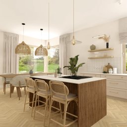 Projektowanie wnętrz Sylwia Rygielska - Jasna kuchnia z wyspą i rattanowymi krzesłami barowymi, widok na zieleń za oknem. Naturalne materiały i ciepłe oświetlenie tworzą przytulną atmosferę.