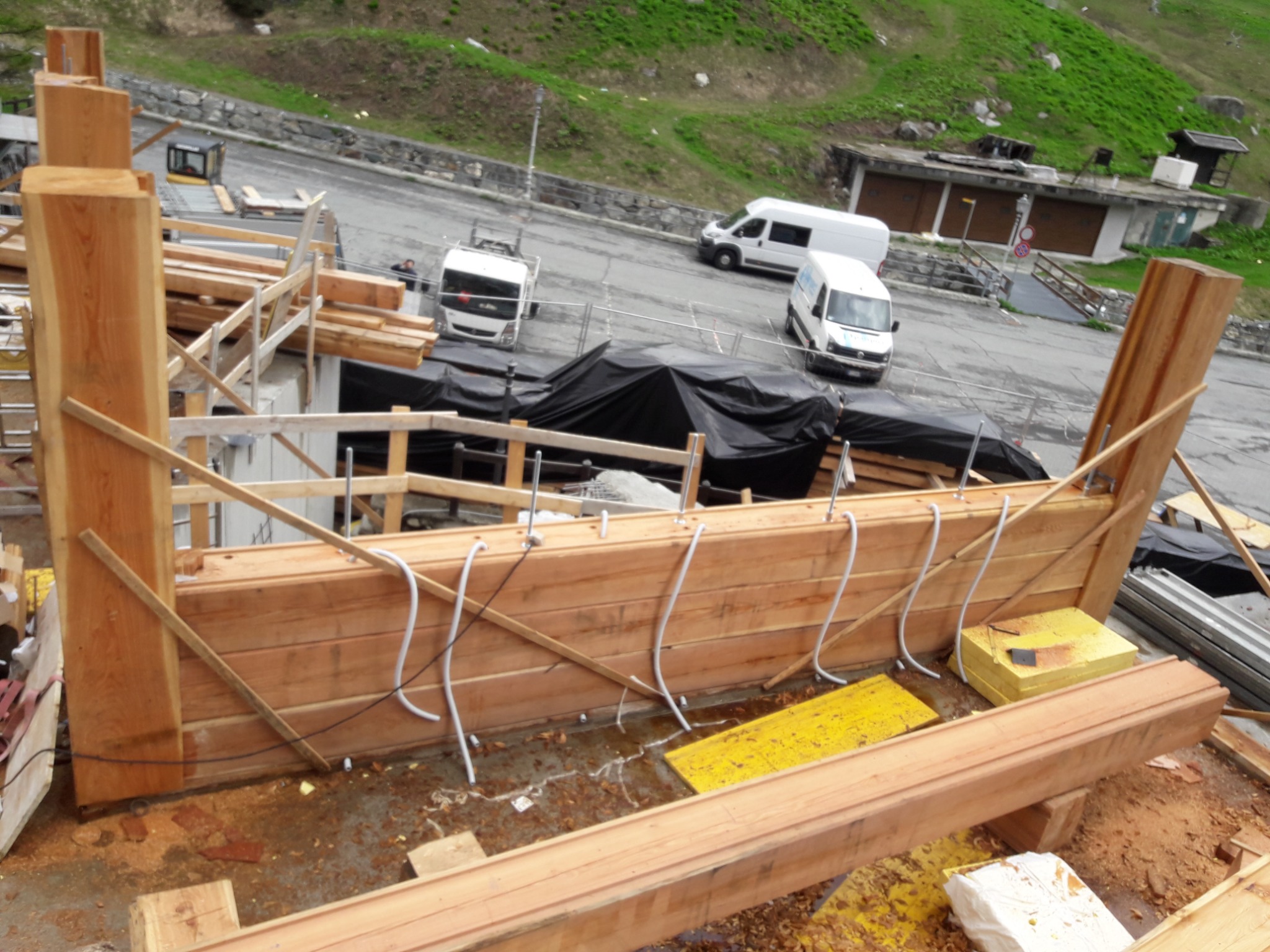 Konstrukcja z bali modrzewiowych o grubości 40cm, prawdopodobnie z importu włoskiego, w trakcie montażu na placu budowy, widoczne elementy mocujące i zabezpieczające.