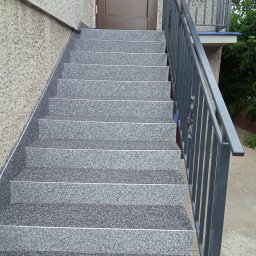 FIRMA REMONTOWO WYKOŃCZENIOWA PAWEŁ SARNA - Zewnętrzne schody wejściowe wyłożone szarą, drobnoziarnistą mozaiką z metalowymi listwami antypoślizgowymi, prowadzące do brązowych drzwi wejściowych z metalową balustradą po prawej stronie.