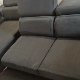 Szara, modułowa sofa z widocznymi śladami wilgoci po czyszczeniu, ukazująca odświeżoną tapicerkę.