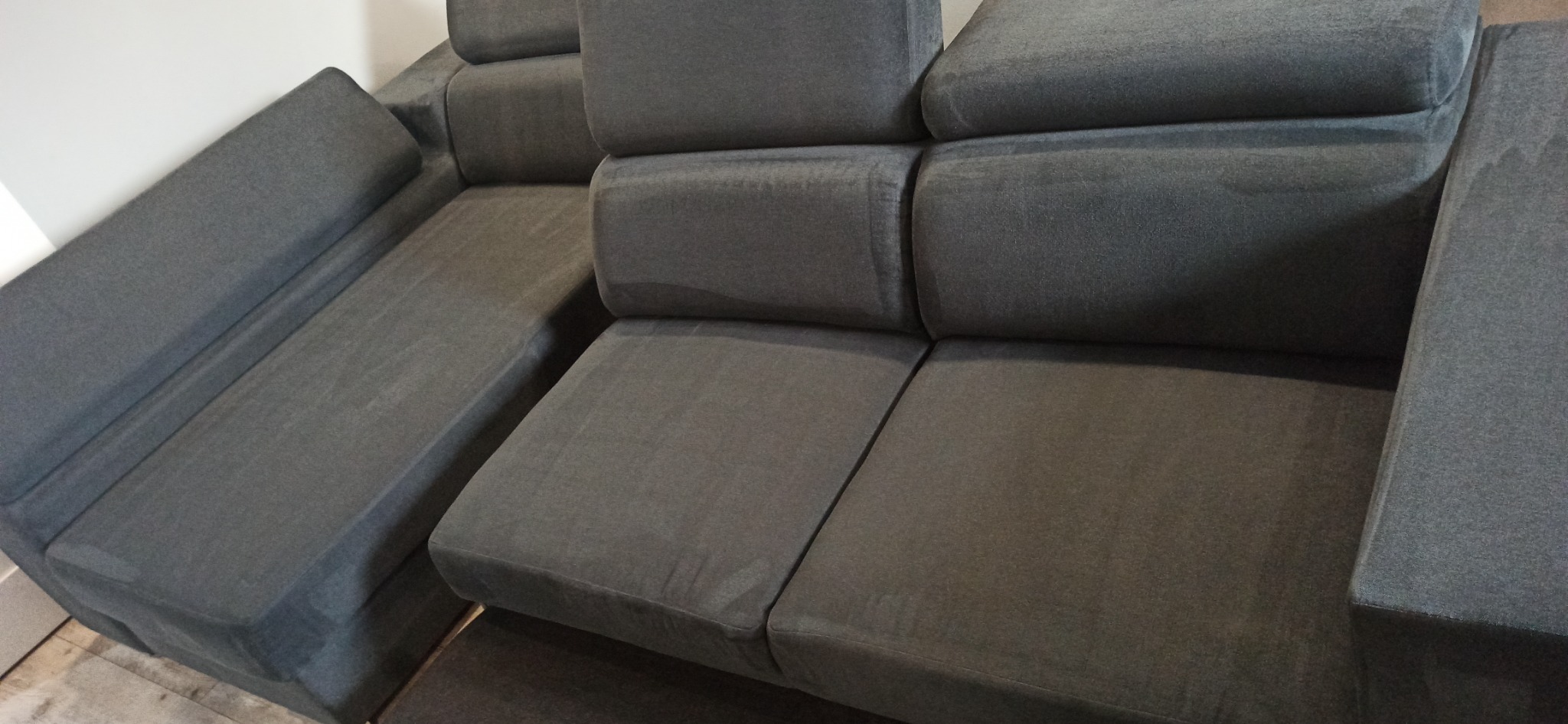 Szara, modułowa sofa z widocznymi śladami wilgoci po czyszczeniu, ukazująca odświeżoną tapicerkę.