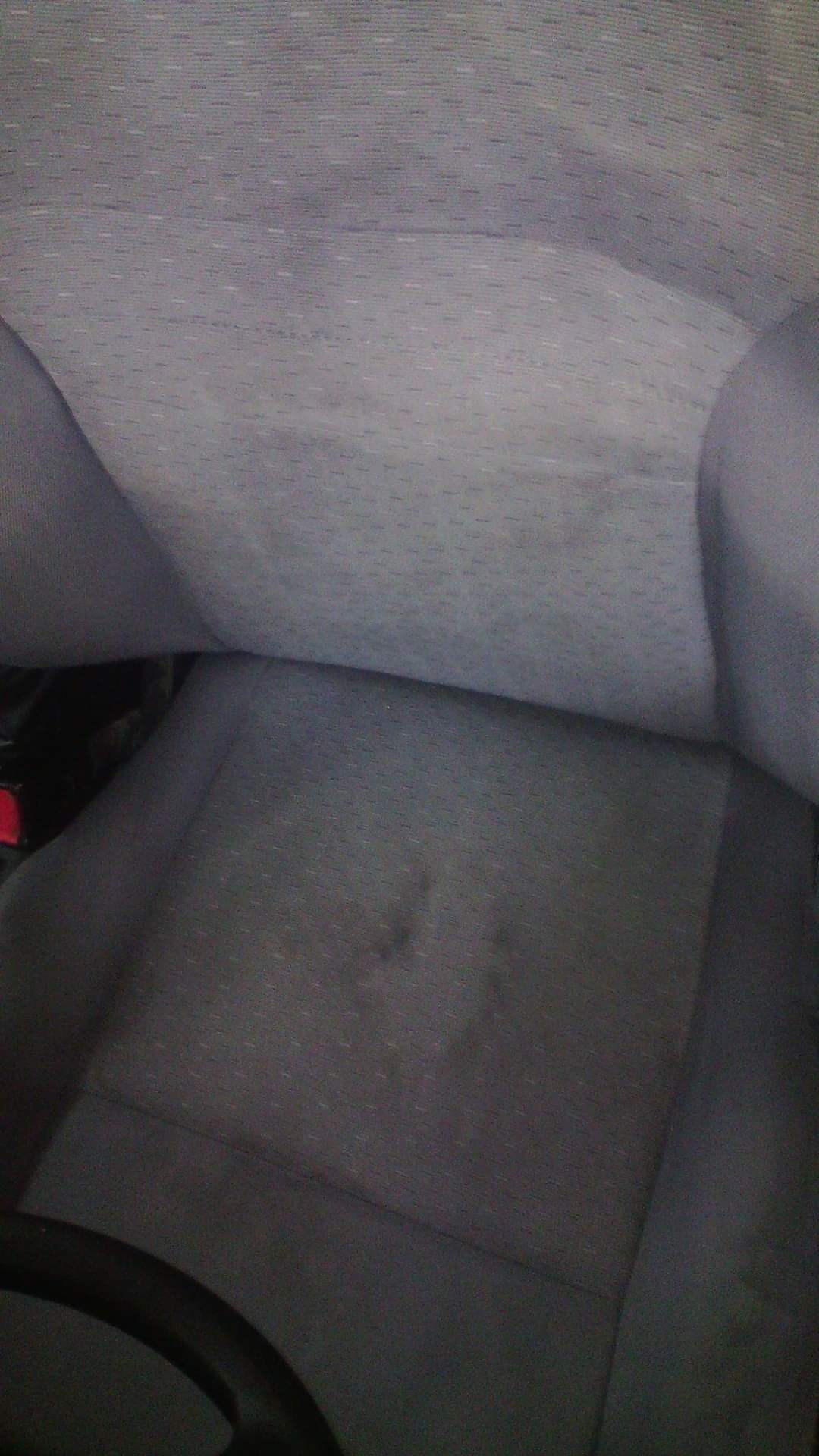 Brudna, szara tapicerka samochodowa z widocznymi plamami na siedzisku.