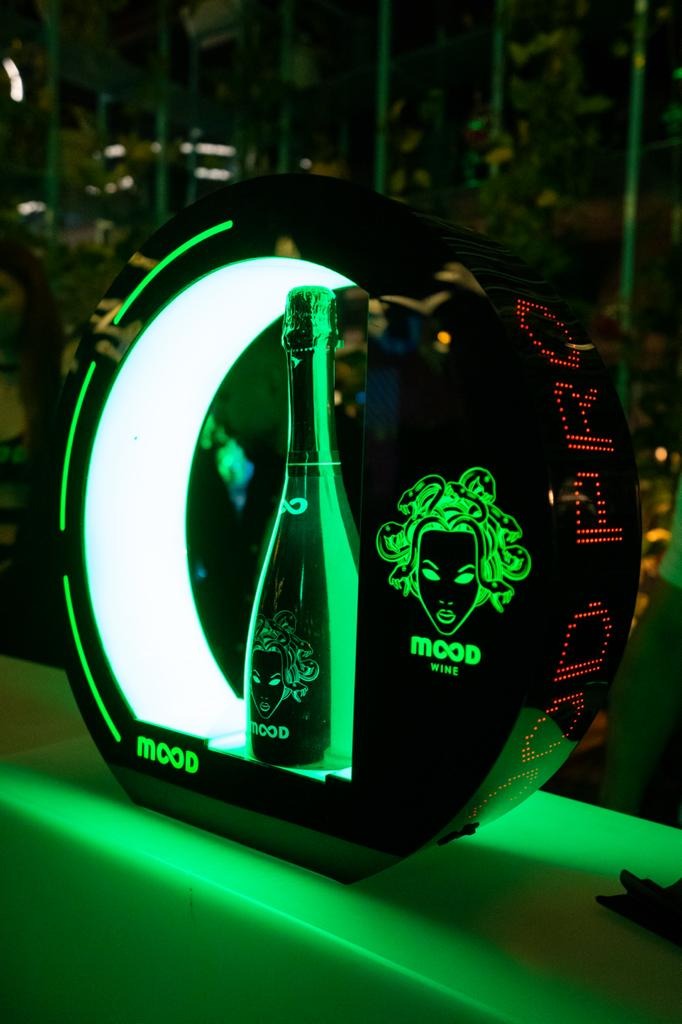 Butelka wina Mood w podświetlanej, okrągłej ekspozycji z motywem Meduzy, świecąca neonową zielenią.