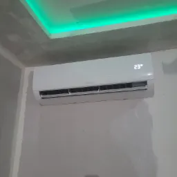 Nowoczesny klimatyzator marki Hyundai zamontowany na ścianie w surowym stanie, widoczny wyświetlacz z temperaturą 23 stopnie Celsjusza, zielone oświetlenie LED na suficie, ściany w trakcie...