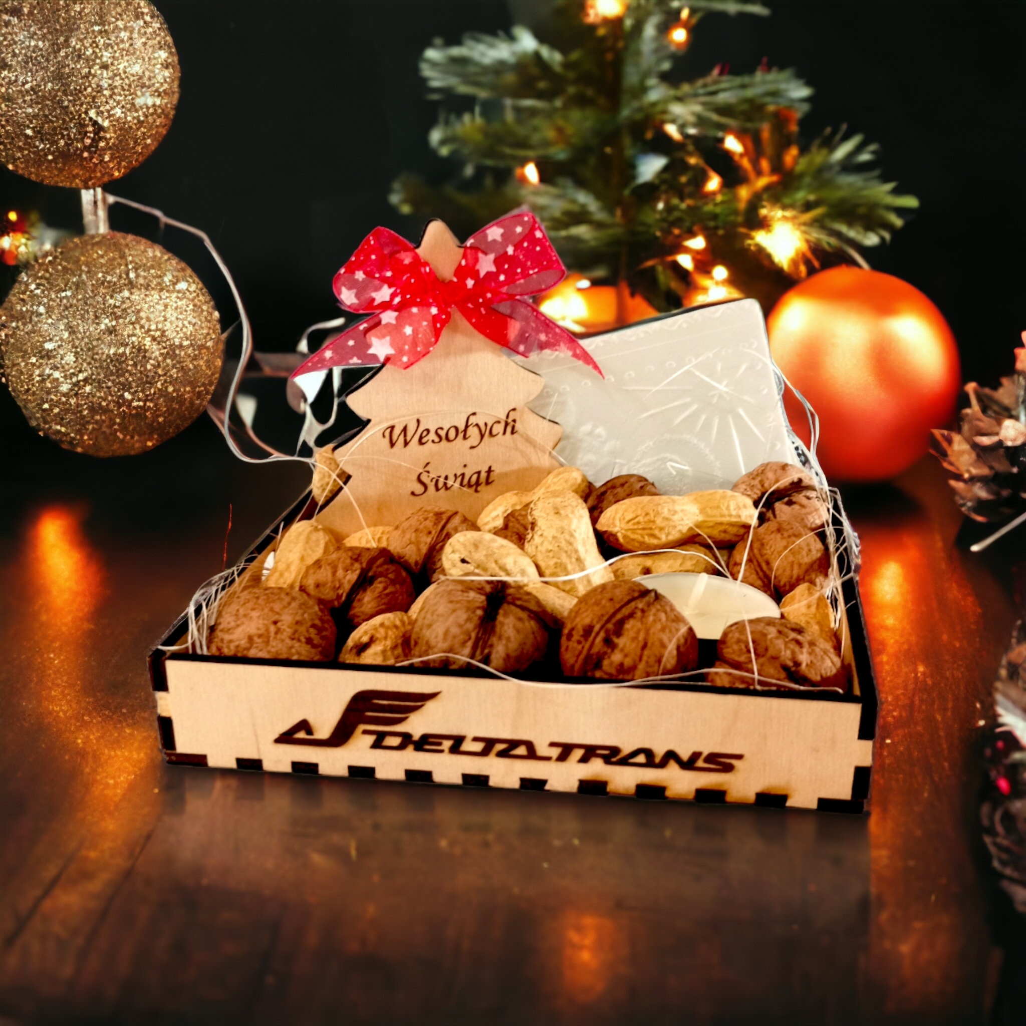 Świąteczny kosz prezentowy z orzechami włoskimi i ziemnymi w drewnianym pudełku z wyciętym logo Delta Trans, ozdobiony drewnianą choinką z napisem 'Wesołych Świąt' i czerwoną kokardką w gwiazdki,...