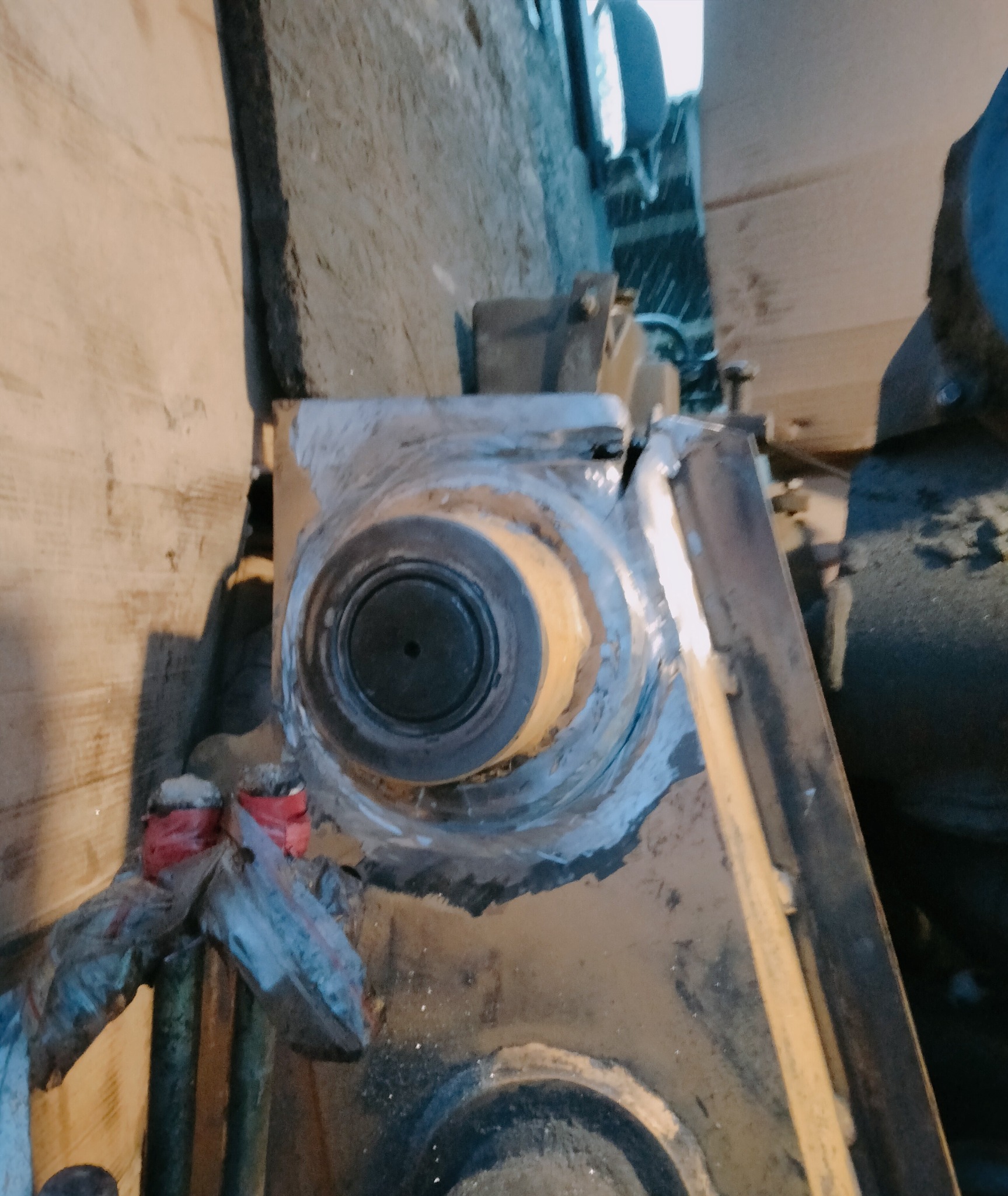 Spoina wokół metalowego elementu maszyny, widoczne ślady obróbki i przygotowania do spawania. Detal z bliska, surowy wygląd.