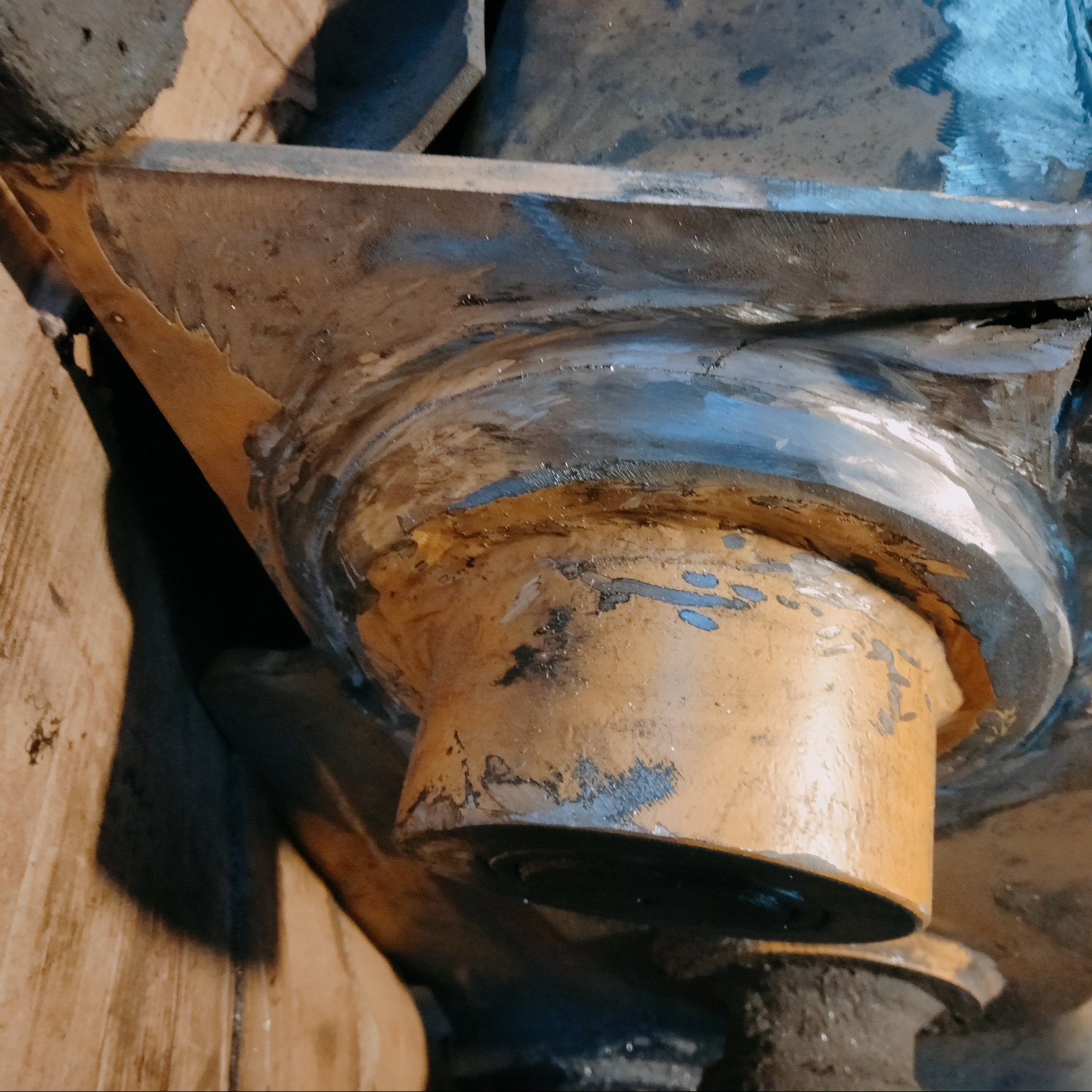 Żółta, metalowa konstrukcja po spawaniu, widoczne ślady obróbki i niedoskonałości spoiny. Detal z bliska, surowy wygląd.