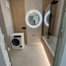 Art_HomeSERWIS Vitalii Kvasniuk - Wykończona łazienka z pralką Electrolux, podświetlanym lustrem LED, czarną armaturą i panelami dekoracyjnymi na ścianach, widok z perspektywy wejścia.