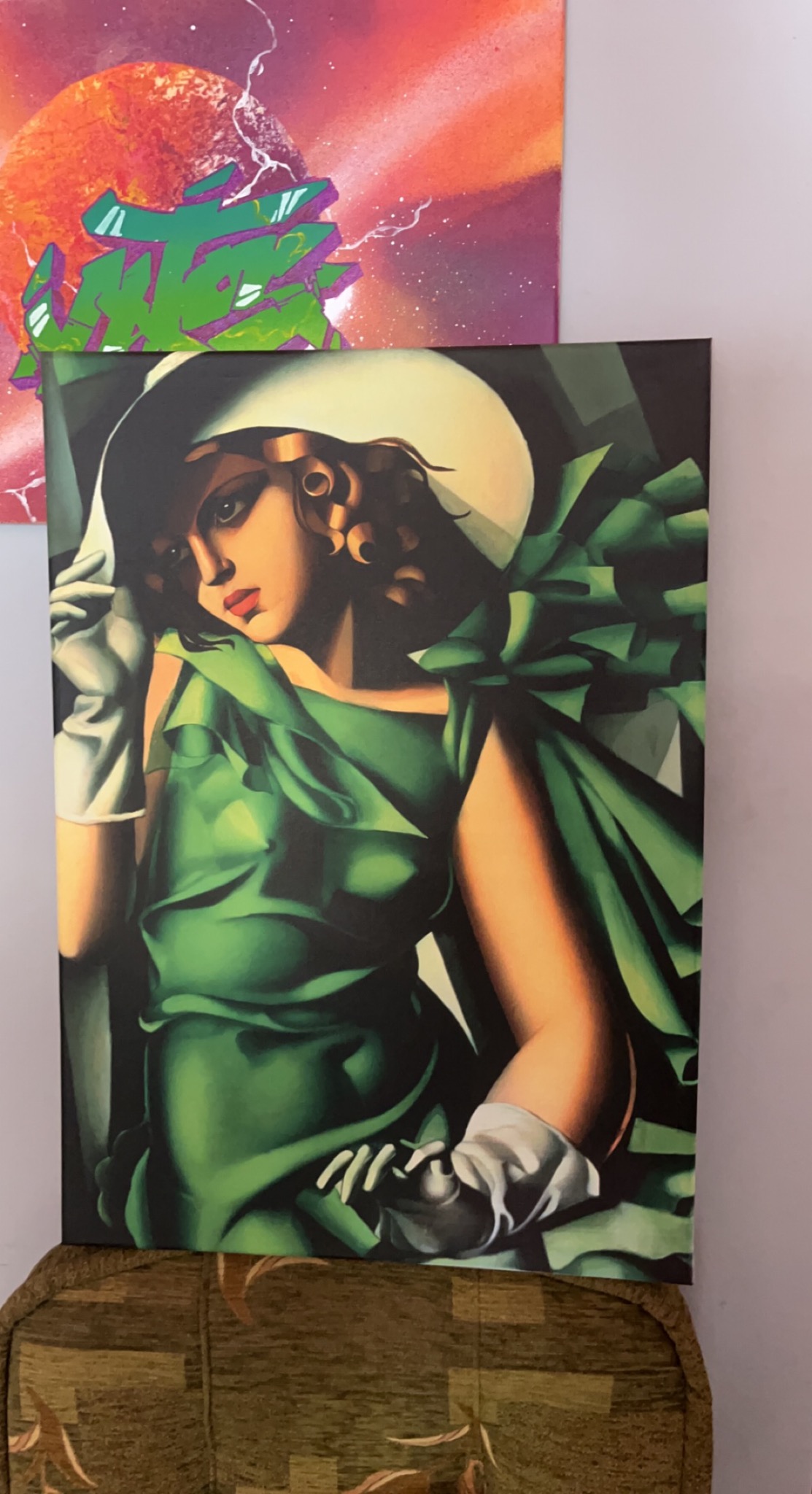Portret kobiety w zielonej sukni i kapeluszu, w stylu art deco, na płótnie, obok abstrakcyjnego graffiti na ścianie.