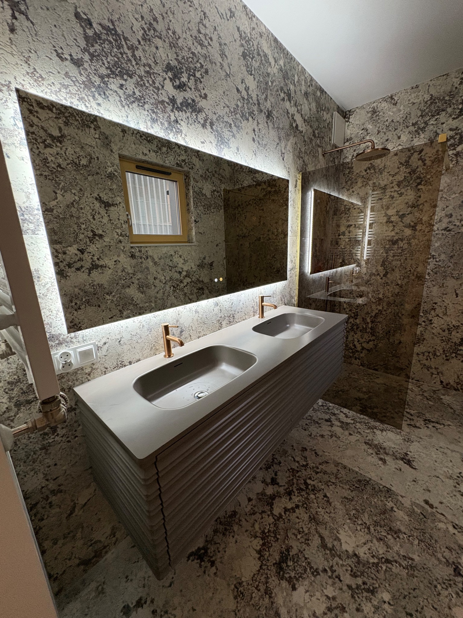 Wykończona łazienka w Luboniu z podwójną umywalką o żłobkowanej podstawie, dużym lustrem z podświetleniem LED i ścianami wykończonymi w dekoracyjnej strukturze.