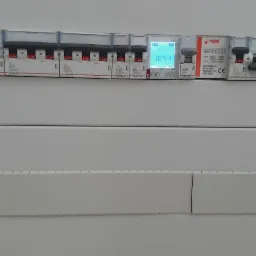 Rozdzielnica elektryczna z zainstalowanymi bezpiecznikami różnicowoprądowymi i wyłącznikami nadprądowymi różnych marek, w tym Legrand i Relpol, z wyświetlaczem wskazującym godzinę 10:54.