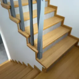 Drewniane schody z szarymi balustradami, widok z góry, jasne drewno, minimalistyczny design, nowoczesne wykończenie.