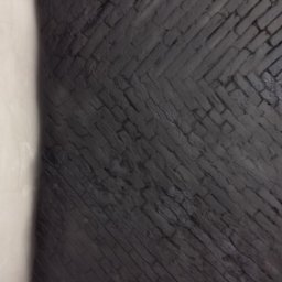 SASIUK SPÓŁKA Z OGRANICZONĄ ODPOWIEDZIALNOŚCIĄ - Ciemnoszara ściana z cegieł ułożonych w jodełkę, częściowo przysłonięta jasną ścianą.