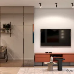 Salon z tapetą w tropikalne ptaki, lustrzaną szafą w zabudowie, pomarańczową szafką RTV i telewizorem, oświetleniem punktowym i stolikami kawowymi na puszystym dywanie.