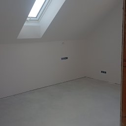 Set-Bud usługi remontowo-wykończeniowe - Poddasze po gładziowaniu i malowaniu na biało, widoczne okno dachowe i gniazdka elektryczne. Świeżo wykończone wnętrze z jasnym światłem słonecznym.