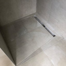 Maciej żołecki - Beżowe płytki podłogowe i ścienne w kabinie prysznicowej z odpływem liniowym ze stali nierdzewnej.