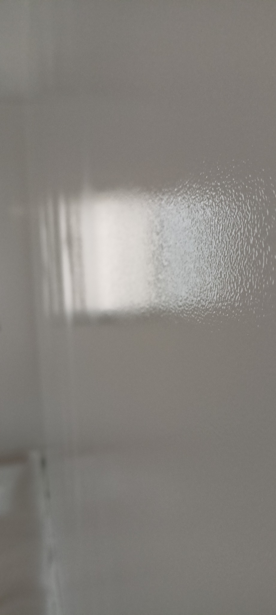 Świeżo pomalowana, gładka, szara ściana z delikatną fakturą i widocznym odbiciem światła.