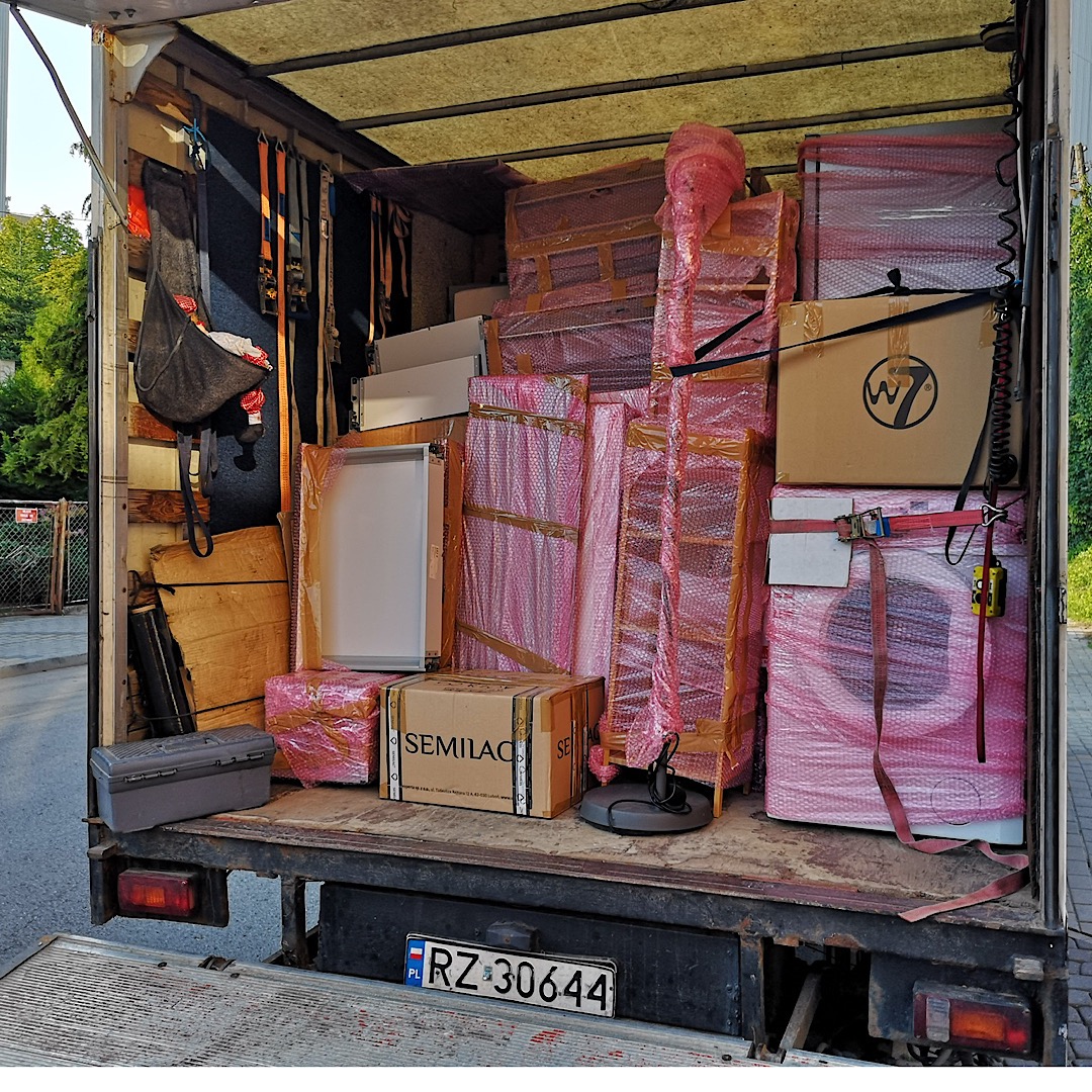Wnętrze samochodu dostawczego wypełnione po brzegi zapakowanymi meblami i sprzętami AGD, zabezpieczonymi folią bąbelkową i taśmami, podczas transportu na terenie Rzeszowa.