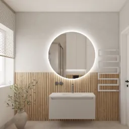 Nowoczesna łazienka z okrągłym lustrem podświetlanym LED, drewnianą boazerią pionową, białą szafką umywalkową i grzejnikiem drabinkowym. W lustrze odbicie kabiny prysznicowej.