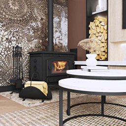 Decoria Studio Patrycja Tachmańska - Salon z czarnym piecem kominkowym, dekoracyjną ścianą imitującą skórę węża, zestawem narzędzi kominkowych i stolikami kawowymi z białymi blatami na plecionym dywanie.