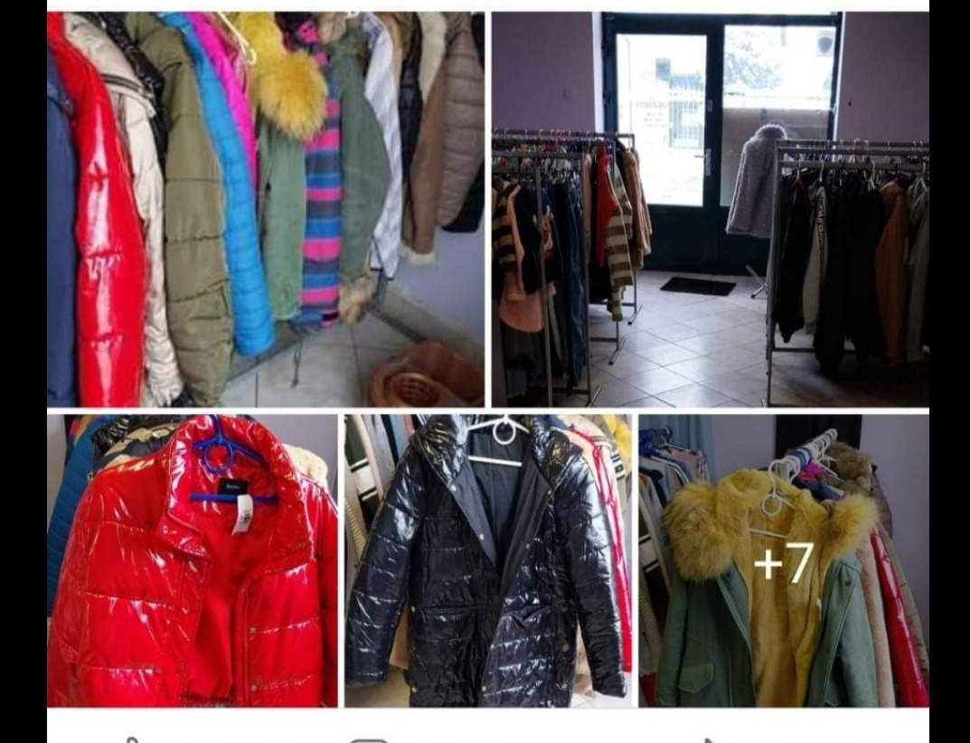 Różnorodny asortyment kurtek zimowych i przejściowych na wieszakach w sklepie z odzieżą używaną, widoczne kurtki w kolorach czerwonym, czarnym, zielonym i niebieskim, niektóre z futrzanymi kapturami.