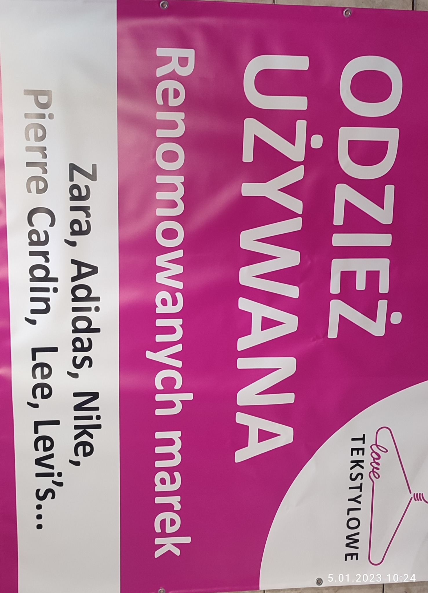 Różowy baner reklamowy z białymi napisami: 'Odzież Używana', 'Renomowanych marek', 'Zara, Adidas, Nike, Pierre Cardin, Lee, Levi's...', logo 'Love Tekstylne'.