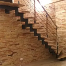 Schody drewniane z metalowymi elementami w stylu loftowym na tle ceglanej ściany w Kalwarii Zebrzydowskiej.